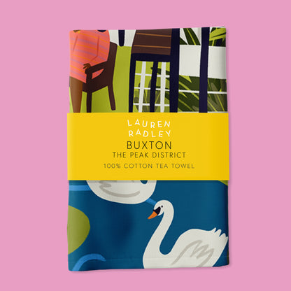 Tea towel with colorful design and swan illustration on a pink background